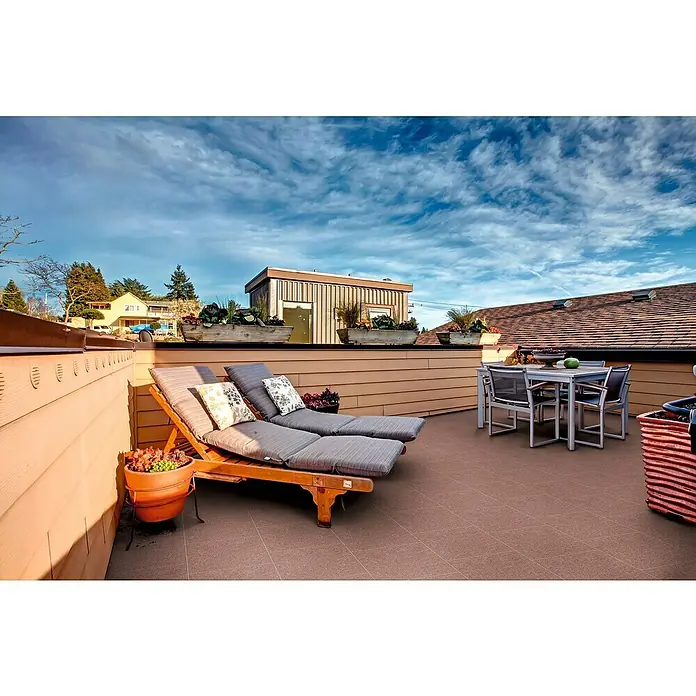 Diephaus Terrassenplatte Phoenix40 x 40 x 4 cm, Rot, Beton - Eine Terrasse mit Loungemöbeln, einem Esstisch und üppigen Pflanzgefäßen bietet einen stilvollen Rückzugsort im Freien mit Ausblick.