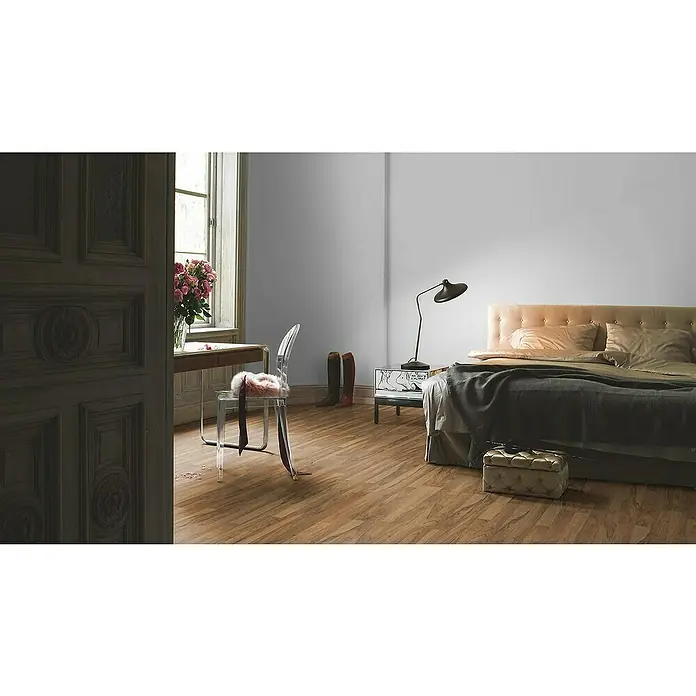 Parador Laminat Basic 200 - Nussbaum, Schiffsboden, 1.285 x 194 x 7 mm - Einladendes Schlafzimmer mit Holzboden, Nachttischlampe und einem bequemen Bett. Das Design strahlt Wärme und Eleganz aus.