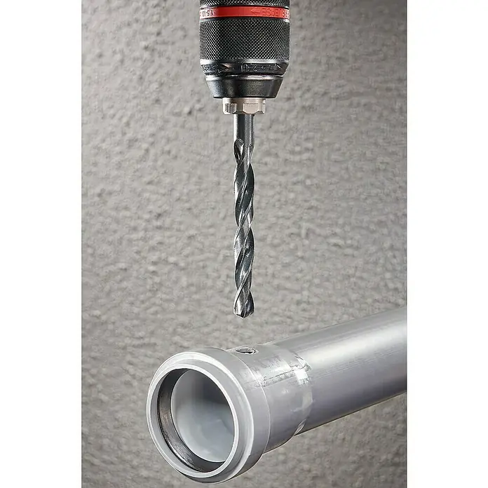 Wolfcraft Metallbohrer rollgewalzt - Durchmesser Bohrer: 10 mm - Eine Bohrmaschine mit einem Spiralbohrer, die bereit ist, ein Loch in ein graues Kunststoffrohr zu bohren, im Hintergrund eine graue Wand.