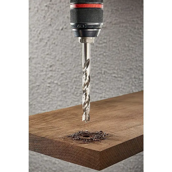 Wolfcraft Holzbohrer HSS Professional - Durchmesser Bohrer: 10 mm - Das Bild zeigt einen Bohrer, der in ein Holzbrett bohrt und Späne erzeugt. Der Bohrer ist spiralförmig und aus Metall.