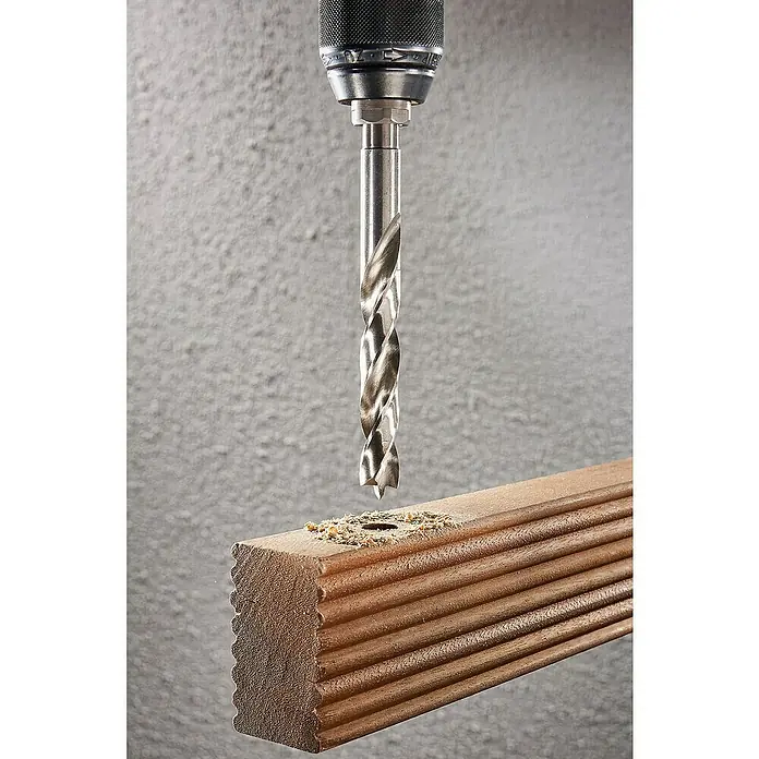 Wolfcraft Holzbohrer HSS Professional - Durchmesser Bohrer: 10 mm - Das Bild zeigt einen Bohrer, der ein Loch in ein Stück geriffeltes Holz bohrt, wobei Holzspäne um das Loch herum zu sehen sind.