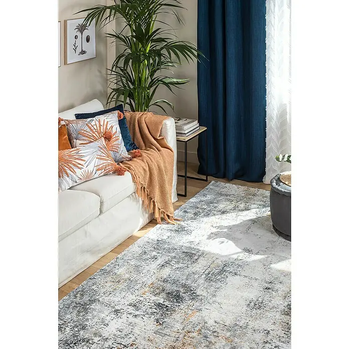 Cojín Elia - 50 x 30 cm, Textil, Melocotón, Rectangular - Una elegante sala de estar con una alfombra abstracta en tonos de gris, negro y dorado, que añade un toque moderno a la habitación.