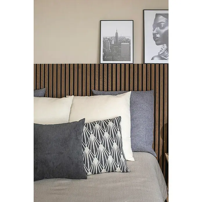 Cojín Pana - 45 x 45 cm, Poliéster, Gris, Cuadrado - Interior de dormitorio con cabecero de madera, varios cojines en tonos grises y blancos y estampados artísticos decorativos en la pared.
