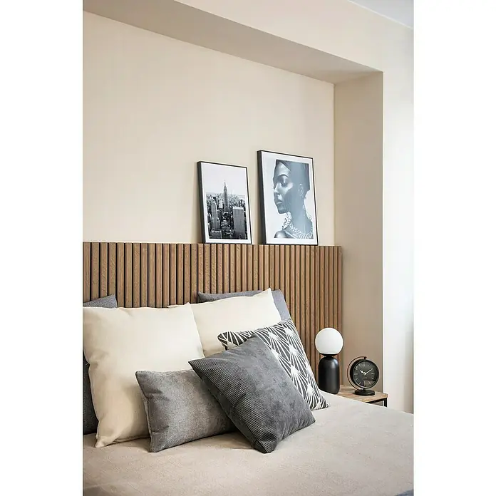Cojín Pana - 45 x 45 cm, Poliéster, Gris, Cuadrado - Elegante interior de dormitorio con un cabecero de madera elegante, cojines decorativos y obras de arte enmarcadas que crean un ambiente sereno.