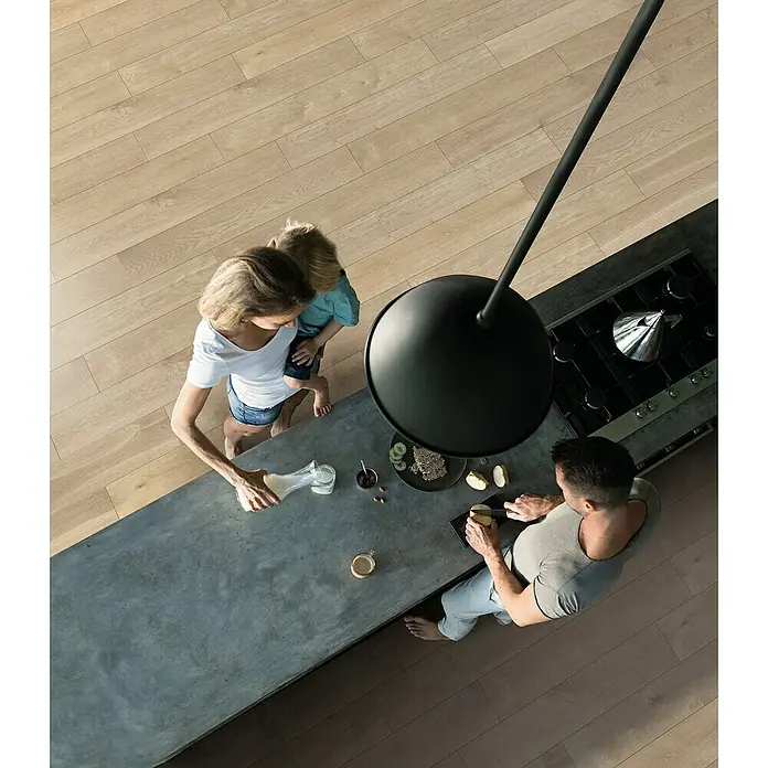 Krono Original Vinylboden Rocko 5+1 - Rope, Landhausdiele, 1.210 x 192 x 6 mm - Draufsicht auf eine Familie in einer Küche. Ein besonderes Merkmal ist die große, schwarze Pendelleuchte über der Kücheninsel.