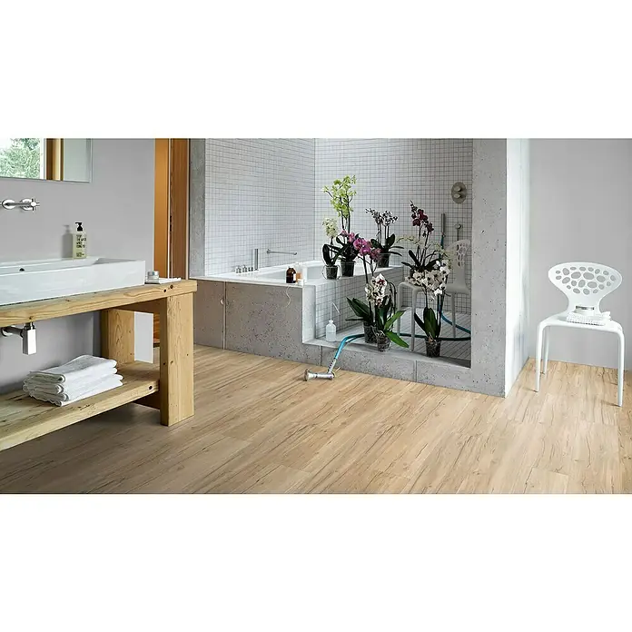 Parador Vinylbodenmuster Basic 30 Eiche Memory geschliffen - 200 x 216 x 9,4 mm, Landhausdiele - Helles Badezimmer mit Holzfußboden, Waschtisch, Badewanne und Blumen. Der Holzboden verleiht dem Raum Wärme und Natürlichkeit.