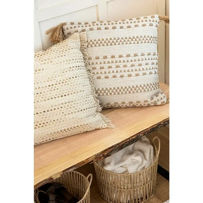 Cojín Dakira - 45 x 45 cm, Textil, Natural, Cuadrado - Cojines decorativos con flecos y patrones geométricos en un banco de madera, con cestas de almacenamiento debajo.