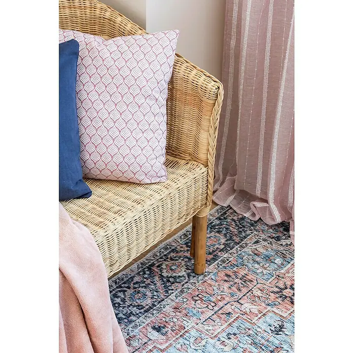 Cortina con ollaos Daniele - An x Al: 140 x 260 cm, Rosa - Primer plano de una silla de ratán con cojines decorativos y una manta, mostrando una decoración del hogar acogedora y elegante.
