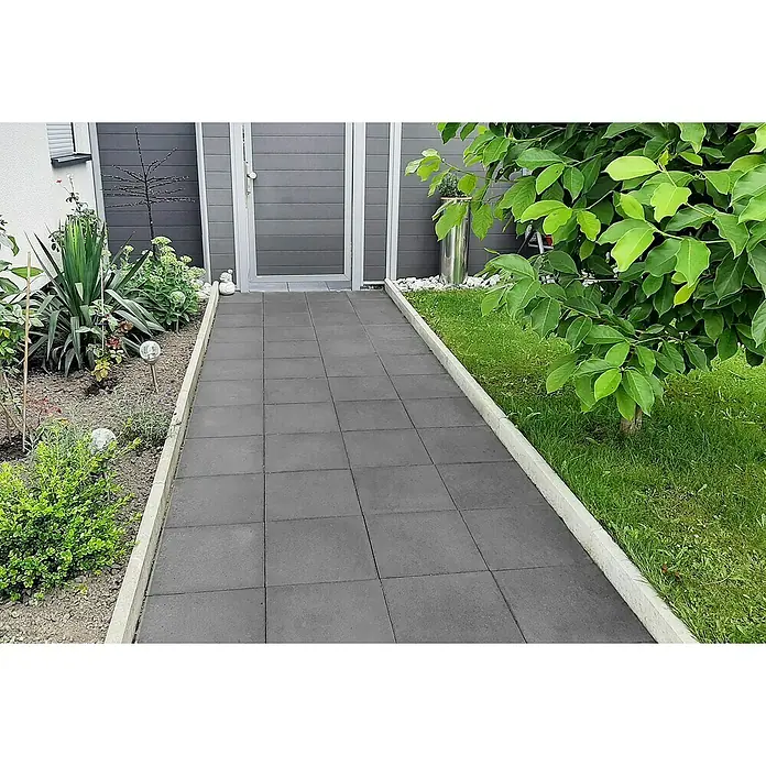 EHL GehwegplatteAnthrazit, 40 x 40 x 5 cm, Beton - Der Gehweg ist mit quadratischen Betonplatten gepflastert und mit hellen Bordsteinen eingefasst, die zu einer grauen Haustür führen.
