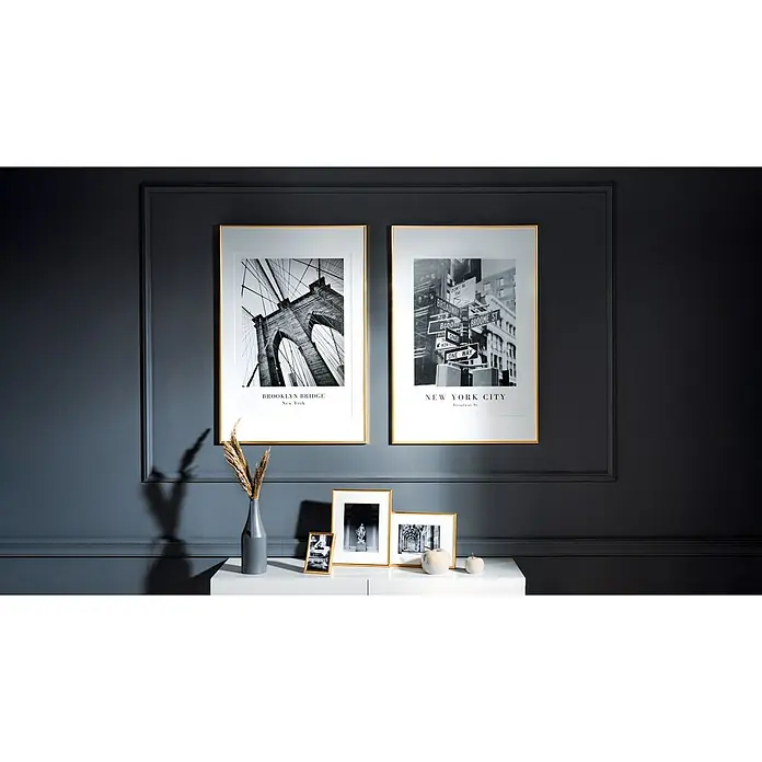 Kunststoffrahmen - 61 x 91,5 cm, Gold - Das Arrangement an einer anthrazitfarbenen Wand mit stilvollen NYC-Wandbildern in goldenen Rahmen und Deko-Elementen auf einer weißen Kommode.