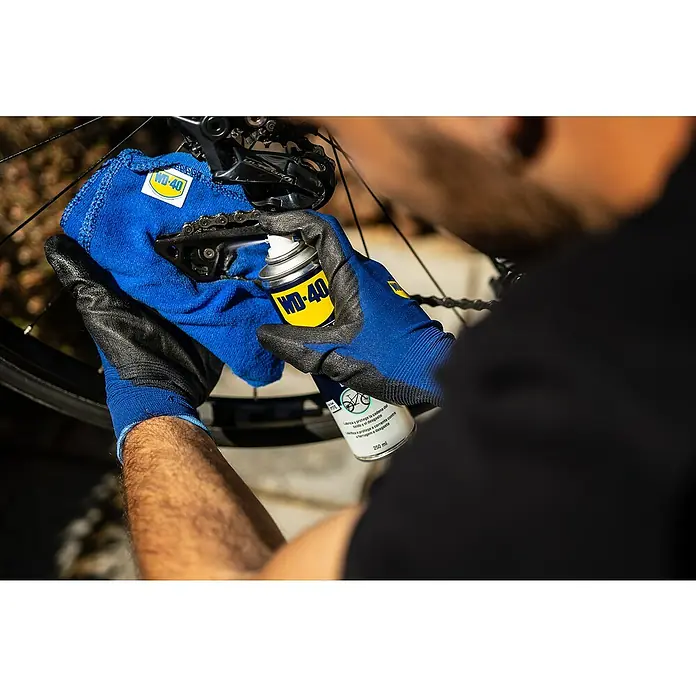 WD-40 Bike Aceite para cadenas Total - 250 ml - Primer plano de una persona que mantiene una cadena de bicicleta con aerosol para cadenas WD-40 para optimizar su vida útil y rendimiento.
