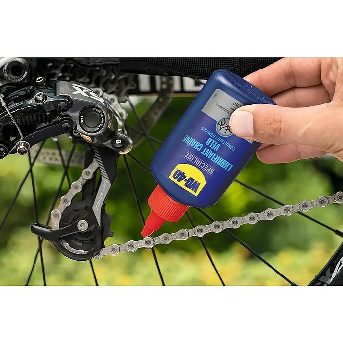WD-40 Bike Lubricante ambientes húmedos - 100 ml, Apto para: Cadenas de bicicleta - La imagen muestra lubricante de cadena de bicicleta WD-40 que se aplica a una cadena de bicicleta.