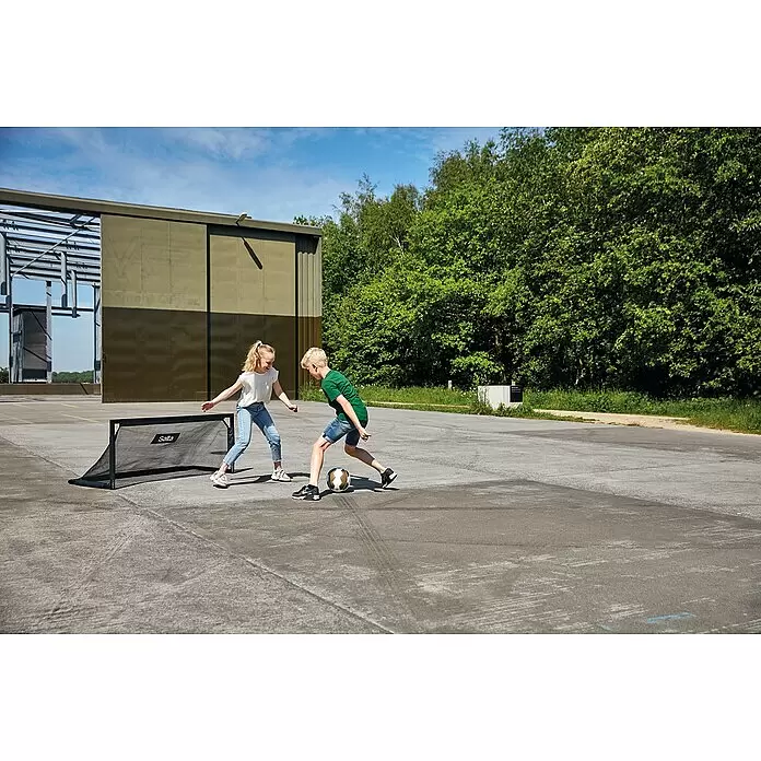 Salta Fußballtor Techniq - 150 x 60 x 60 cm, Schwarz - Schwarzes tragbares Salta Fußballtor, von zwei Kindern im Freien genutzt.