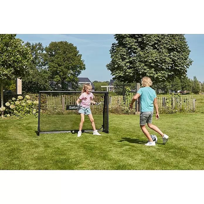 Salta Fußballtor - 180 x 60 x 120 cm, Schwarz - Kinder spielen Fußball mit einem schwarzen Salta Fußballtor im Garten.