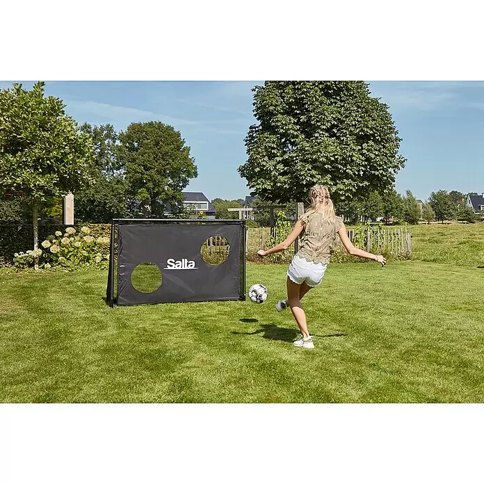 Salta Fußballtor - 180 x 60 x 120 cm, Schwarz - Schwarzes Salta Fußballtor mit zwei runden Ziellöchern, von einer Person beim Fußballspielen genutzt.