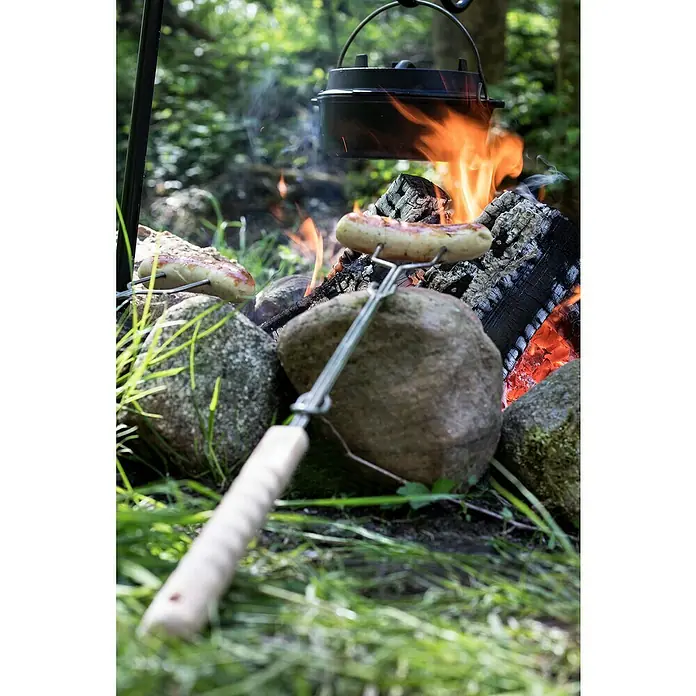 Petromax Grillspieß - Länge: 92 cm, Edelstahl/Buchenholz, Form: Gerade, 2 Stk. - Grillwurst über offenem Feuer zubereitet, dazu ein schwarzer Kessel, der an einem Dreibein hängt, für ein gemütliches Outdoor-Kocherlebnis.