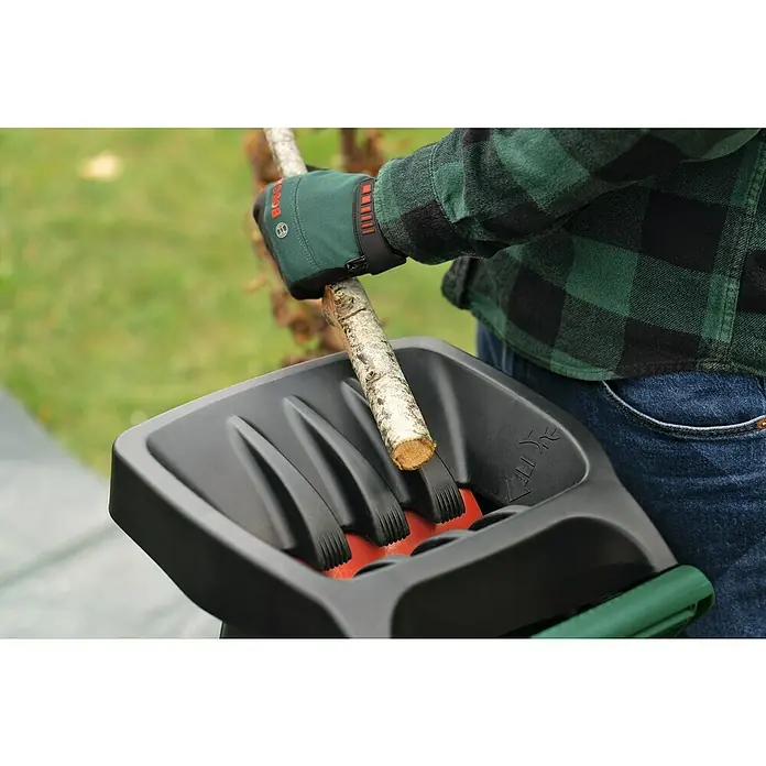 Bosch Elektro-Häcksler AXT RAPID 2200 - Max. Aststärke: 4 cm, 2.200 W - Eine Person füttert einen Bosch-Gartenschredder mit einem Ast. Der Schredder ist schwarz und orange.