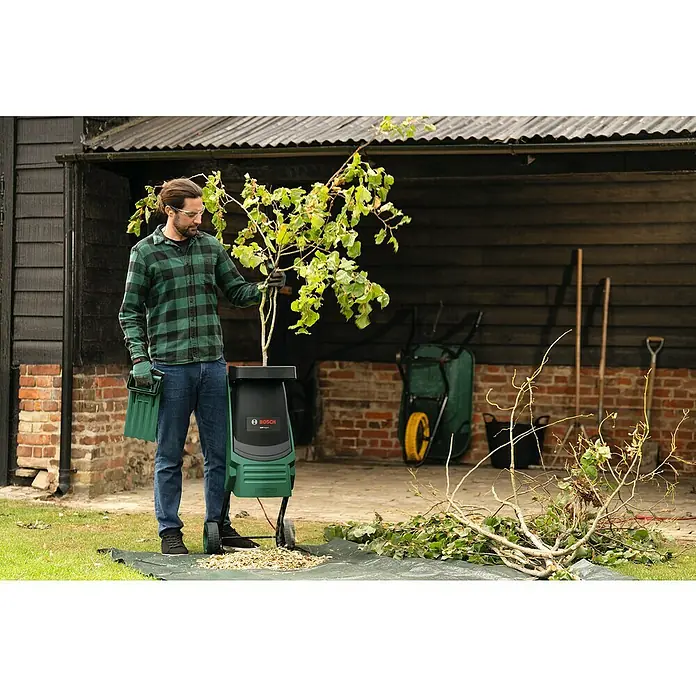 Bosch Elektro-Häcksler AXT RAPID 2200 - Max. Aststärke: 4 cm, 2.200 W - Mann führt Äste in einen Bosch AXT Rapid 2200 Häcksler ein.