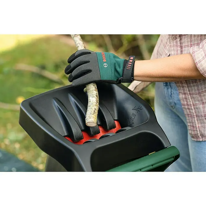 Bosch Elektro-Häcksler AXT RAPID 2200 - Max. Aststärke: 4 cm, 2.200 W - Eine Person benutzt einen Bosch Häcksler mit Handschuhen, um einen Ast zu zerkleinern.