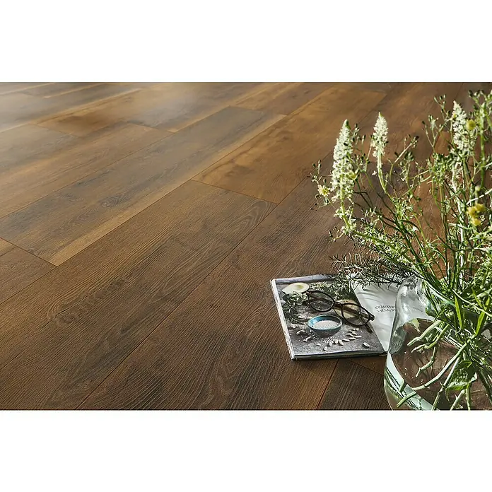 LOGOCLIC Vinto Laminat - Eiche Porto, Landhausdiele, 1.288 x 330 x 8 mm - Nahaufnahme von Laminatboden mit Holzstruktur, Magazin mit Brille und Blumenvase für eine gemütliche Raumatmosphäre.