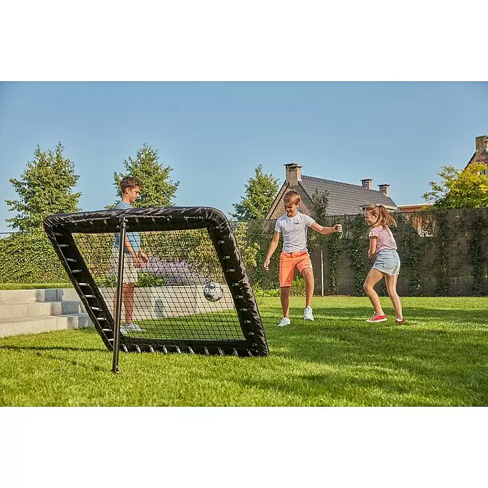 Salta Rebounder Motion - 124 x 124 cm, Schwarz - Schwarzes Fußball-Rebounder-Tor mit sichtbaren Federn und Netz, von Kindern im Garten genutzt.