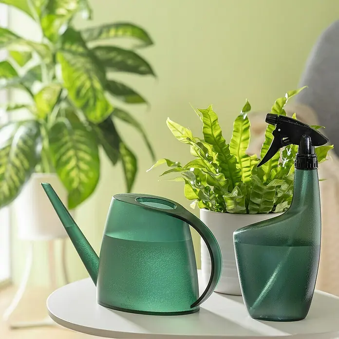 Scheurich Smilla Handsprüher - 0,7 l, Clear Viridian - Grüne Gießkanne und Sprühflasche, unverzichtbare Gartengeräte, stilvoll auf einem Tisch platziert, umgeben von üppigem Grün für die Pflanzenpflege.