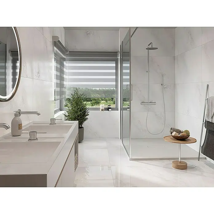 Feinsteinzeugfliese Hydra Weiß - 59,8 x 119,8 cm, Weiß, Glänzend - Helles Badezimmer mit Doppelwaschbecken, Dusche und Fenster mit Blick auf die Natur, das ein Gefühl von Entspannung und Wohlbefinden vermittelt.