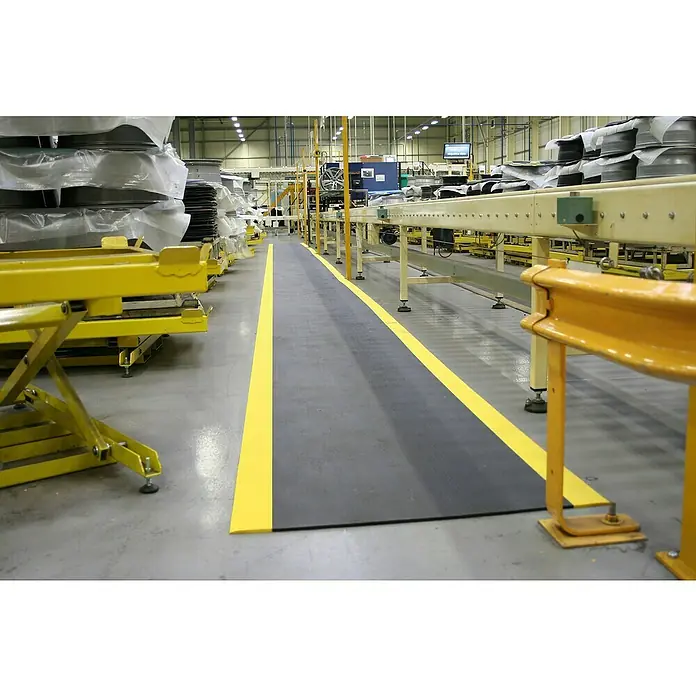 Coba Anti-Ermüdungsmatte Orthomat®-Standard Safety - Breite: 90 cm, Schwarz / Gelb - Ein grauer Sicherheitsläufer mit gelben Markierungen in einer Industrieumgebung für mehr Sicherheit.