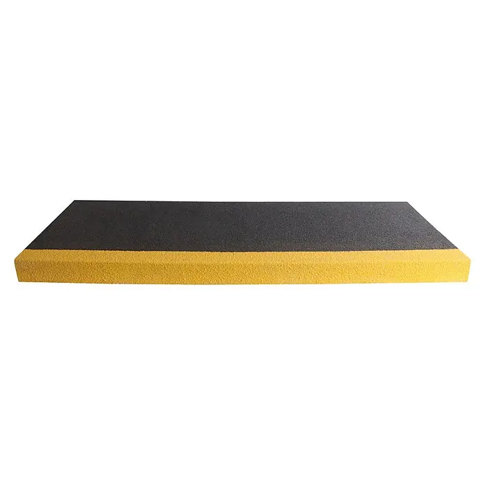 Coba Stufenmatte Grip® Stair Tread - Breite: 100 cm, Schwarz/Gelb - Nahaufnahme eines schwarzen und gelben Bordsteins. Die Textur des Bordsteins ist rau und körnig.