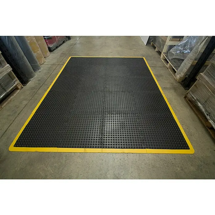 Coba Anti-Ermüdungsmatte Bubblemat Connect Ecke - 50 x 50 cm, Passend für: Coba Connect Safety 28638661 / 28638616 - Schwarze und gelbe Anti-Ermüdungsmatte mit Noppenstruktur auf einem Lagerboden.