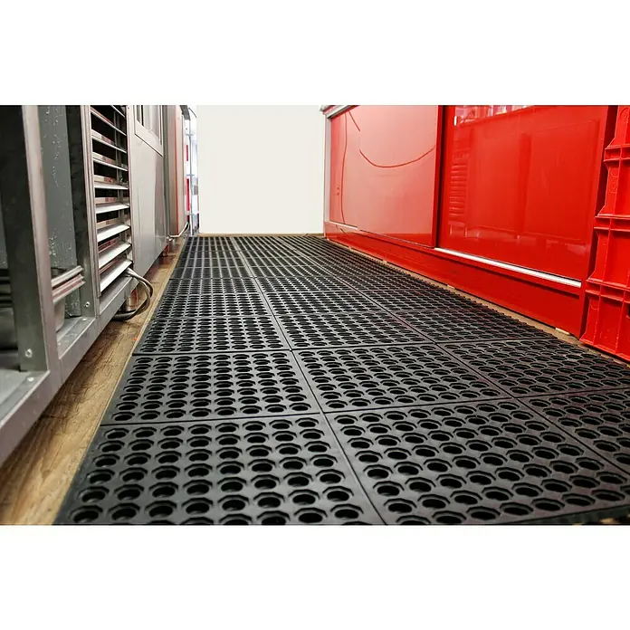 Coba Anti-Ermüdungsmatte Solid Fatigue-Step - Gelochte Oberfläche - Ansicht von schwarzen modularen, perforierten Anti-Ermüdungsmatten auf einem Holzboden, die einen sicheren und komfortablen Arbeitsbereich schaffen.