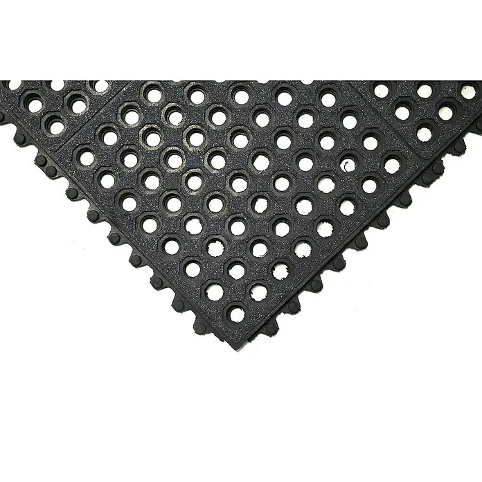 Coba Anti-Ermüdungsmatte Fatigue-Step Grit Top - 90 x 90 cm, Gelochte Oberfläche - Detailaufnahme einer schwarzen, perforierten Gummimatte. Die Matte hat runde Löcher und gezackte Ränder für die Verbindung mit anderen Matten.