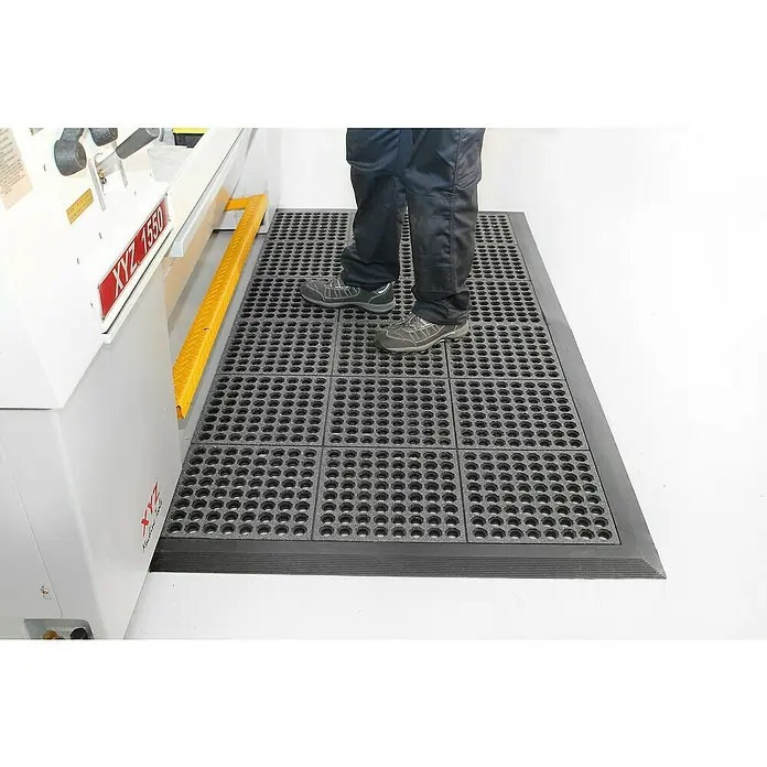 Coba Anti-Ermüdungsmatte Fatigue-Step Grit Top - 90 x 90 cm, Gelochte Oberfläche - Ein Arbeitsplatz mit modularen Anti-Ermüdungsmatten, die für Komfort und Sicherheit in Industrieumgebungen sorgen.