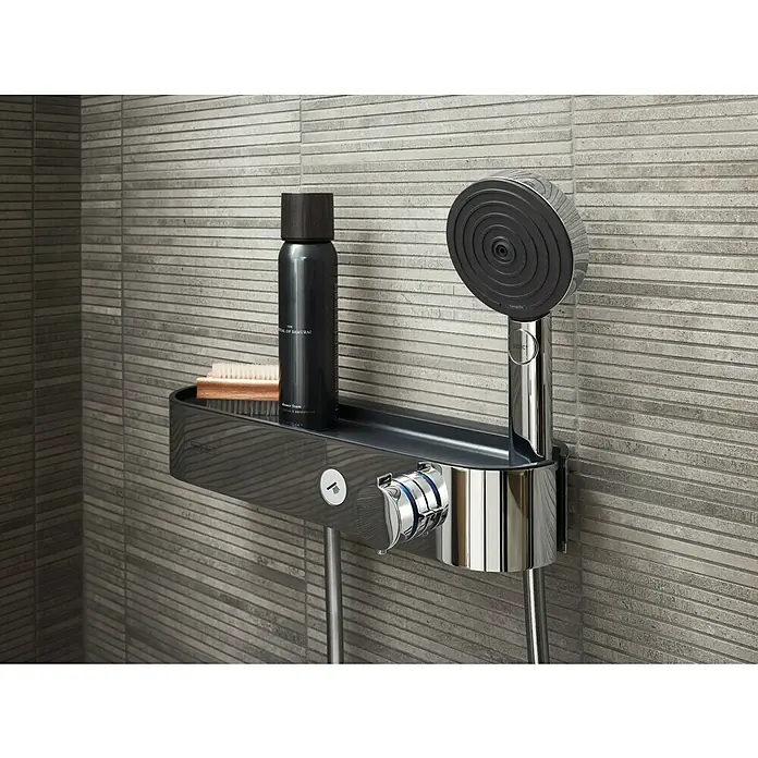 Hansgrohe Pulsify S Handbrause Pulsify Blend - Anzahl Funktionen: 3 Stk., Chrom - Produktaufnahme einer Duscharmatur mit Ablage, Duschkopf und einer Flasche Duschschaum, montiert an einer grauen, horizontal gefliesten Wand.