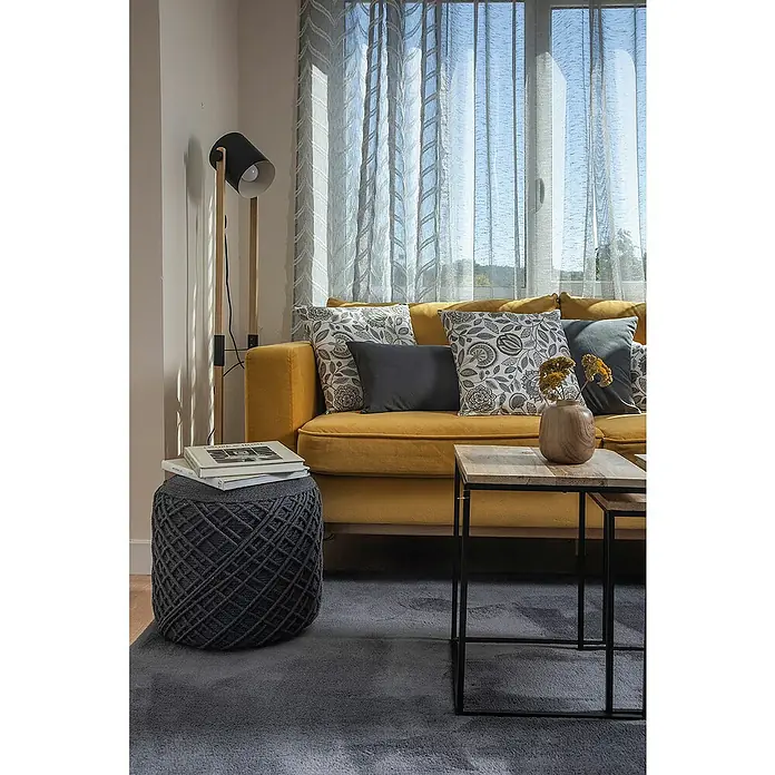 Eglo Hornwood Stehleuchte - Höhe: 140 cm - Gemütliches Wohnzimmer mit senfgelbem Sofa, gemusterten Kissen, Strickhocker und modernem Stehtisch.