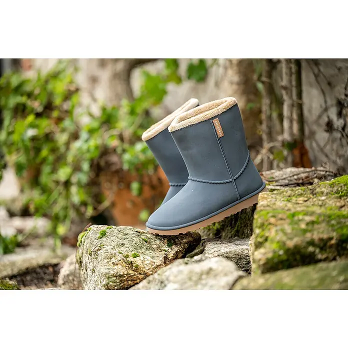 Black Fox Winterstiefel Cheyennetoo - Schuhgröße: 38, Schwarz - Ein Paar graue BLACKFOAM Stiefel mit braunem Saum und Fellfutter stehen auf einem moosbewachsenen Stein.