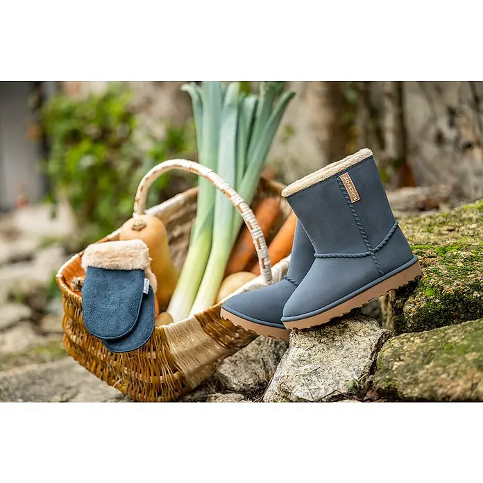 Black Fox Winterstiefel Cheyennetoo - Schuhgröße: 26, Blau - Nahaufnahme von Winterstiefeln und passenden Handschuhen aus marineblauem Wildleder mit hellbraunem Futter und Sohlen neben einem Korb mit Gemüse.