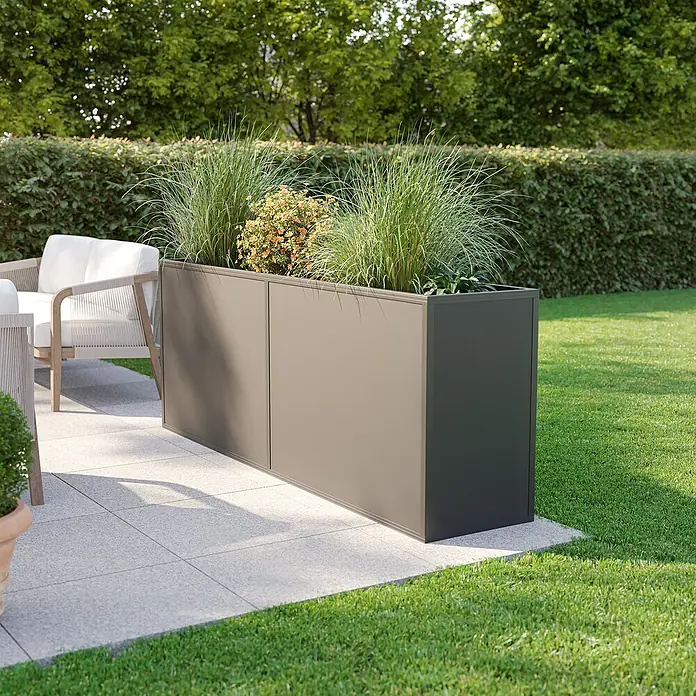 KGT Hochbeet - 2,05 x 0,45 x 0,77 m, Aluminium, Anthrazit - Bild eines rechteckigen, grauen Pflanzgefäßes im Freien, bepflanzt mit Ziergräsern und kleinen Büschen, das eine Terrasse oder einen Garten verschönert.