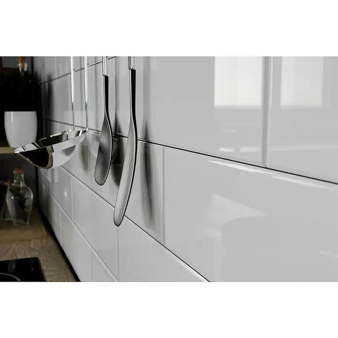 Modern Style Wandfliese Emotion Branco 500 - 9,8 x 29,8 cm, Weiß, Glänzend - Küchenutensilien aus Edelstahl hängen an einer Wand aus weißen glänzenden Fliesen, die eine moderne und saubere Küchenästhetik unterstreichen.