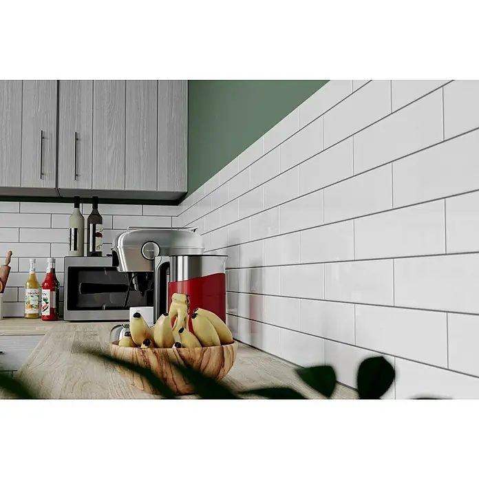 Modern Style Wandfliese Urban Blanco - 7,5 x 30 cm, Weiß, Glänzend - Nahaufnahme einer Küchenarbeitsplatte mit einer Holzschale voller Bananen, Küchengeräten und Fliesen.