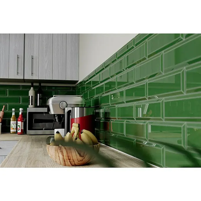 Modern Style Wandfliese Metro Biselado Verde 880 - 9,8 x 29,8 cm, Grün, Glänzend - Ein Küchenstillleben mit grünen Fliesen, Holzarbeitsplatte, Küchengeräten und einer Schale mit Bananen. Die Küche strahlt eine moderne und einladende Atmosphäre aus.