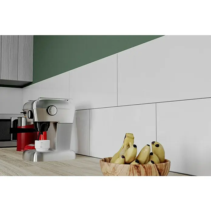 Ambiente by Palazzo Wandfliese Snowwhite New - 30 x 60 cm, Stärke: 9 mm, Weiß, Glänzend - Ein Küchenstillleben mit einer Espressomaschine aus Edelstahl und einer Schale voller Bananen auf einer hellen Arbeitsplatte.