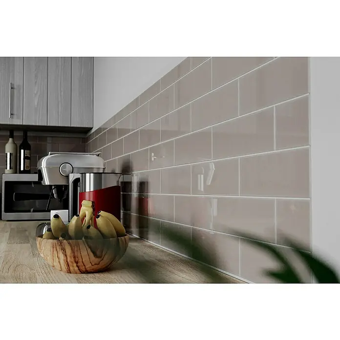 Modern Style Wandfliese Rustic Emotion - 9,8 x 29,8 cm, Grau, Glänzend - Dieses Bild zeigt einen Küchentisch mit einer Schüssel Bananen und einer Kaffeemaschine im Hintergrund, mit grauen Fliesen an der Wand.