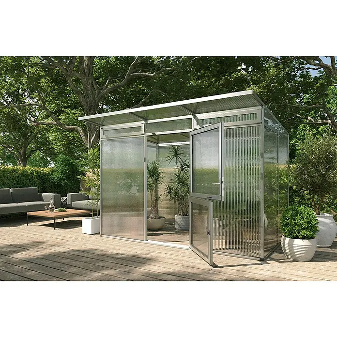 KGT Gewächshaus Santini II - small - Außenmaß inkl. Dachüberstand (B x T): 233 x 155 cm, Material Seitenwand: Kunststoff, 16 mm, Pressblank - Das Bild zeigt ein modernes Gewächshaus mit geöffneter Tür auf einer Holzterrasse, umgeben von üppigem Grün und Bäumen.