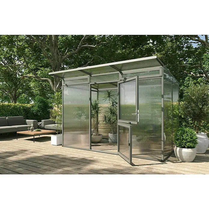 KGT Gewächshaus Santini II - Außenmaß inkl. Dachüberstand (B x T): 297 x 254 cm, Material Seitenwand: Kunststoff, 16 mm, Anthrazit-grau - Ein modernes Gewächshaus mit transluzenten Wänden und offenstehenden Türen, umgeben von Grünpflanzen und einer Sitzecke auf einer Holzterrasse.