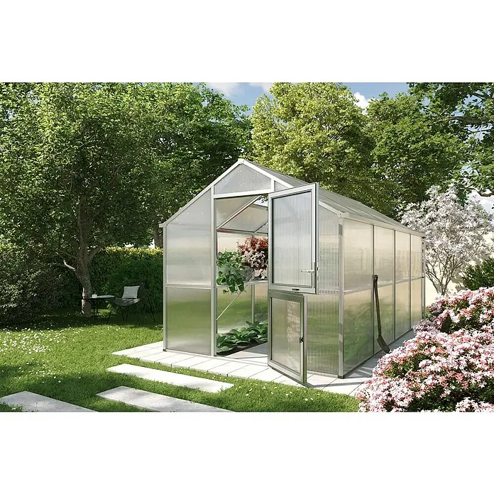 KGT Gewächshaus Iris IV - Außenmaß inkl. Dachüberstand (B x T): 233 x 429 cm, Material Seitenwand: Kunststoff, Pressblank - Ein Gewächshaus im Garten mit geöffneter Tür, umgeben von Blumen und Bäumen, bietet den perfekten Ort für Pflanzenliebhaber.
