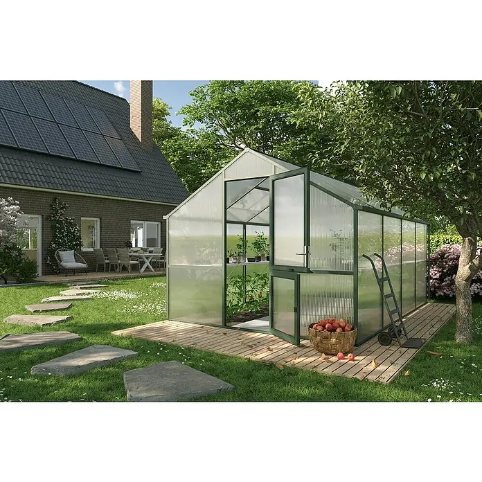 KGT Gewächshaus Nelke IV - Außenmaß inkl. Dachüberstand (B x T): 297 x 429 cm, Material Seitenwand: Kunststoff, 16 mm, Tannengrün - Ein Gewächshaus mit geöffneten Türen steht auf einer Holzterrasse in einem Garten mit einem Korb Äpfel.