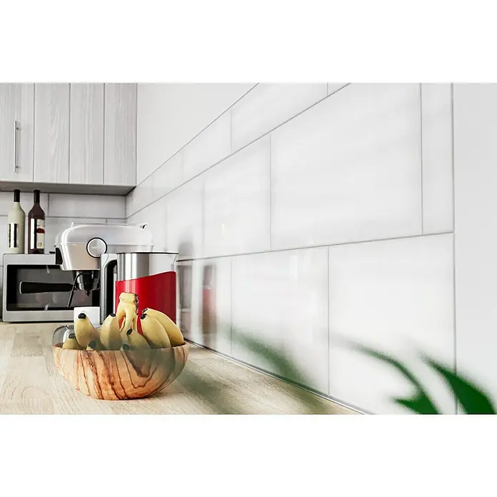 Decocer by Cinca Glow Wandfliese - 25 x 55 cm, Weiß, Glänzend - Nahaufnahme eines hölzernen Obstschale gefüllt mit Bananen auf einer Küchentheke, im Hintergrund eine Kaffeemaschine und Flaschen.