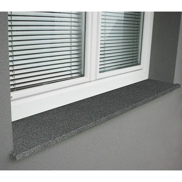 Fensterbank Impakt - 113 x 25 x 2 cm, Anthrazit, Naturstein - Nahaufnahme eines Fensters mit Jalousien und einer Fensterbank aus grauem Granit, die einen eleganten Akzent im Raum setzt.