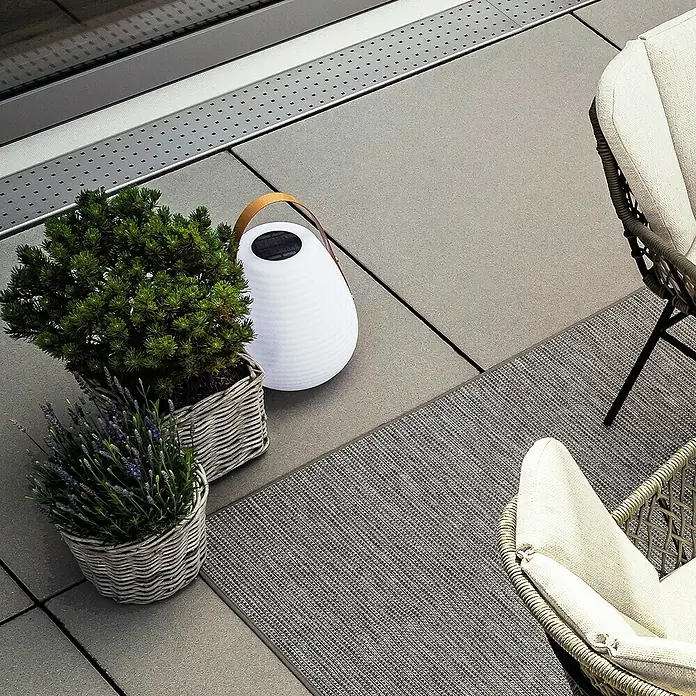 SCHÖNER WOHNEN-Kollektion Akku-Tischleuchte BELL - 2 W, L x B x H: 27 x 27 x 46 cm, Weiß, RGB - Stimmungsvolle Gartengestaltung mit einer dekorativen Laterne, Pflanzen in Körben und bequemen Rattansesseln auf einem modernen Teppich.